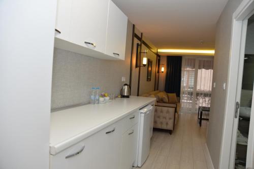特拉布宗Gardenya Suite Hotel的一间带白色橱柜的厨房和一间客厅