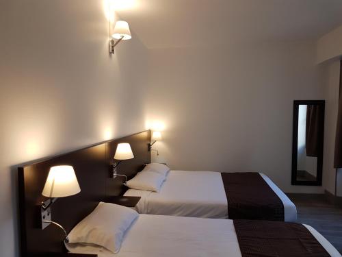 讷韦尔Nevers Hotel的配有2盏灯的酒店客房的2张床