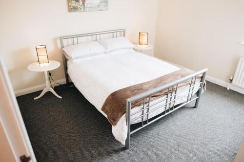 贝尔法斯特Comfortable Belfast city centre apartment的一间卧室配有一张床,两盏台灯放在两张桌子上
