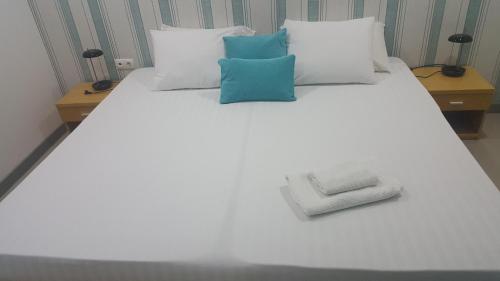 普拉亚Apto T1 Comfort的白色的床和蓝色的白色枕头