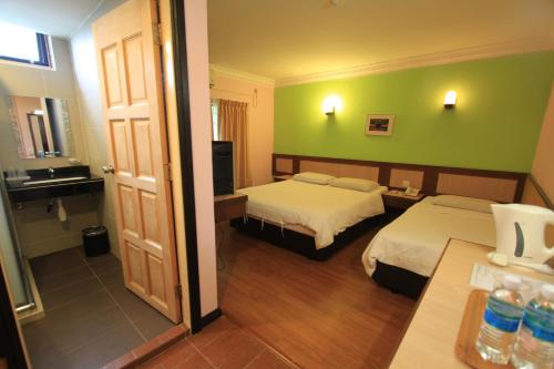 瓜拉丁加奴伊恩宾馆的酒店客房设有两张床和绿色的墙壁。