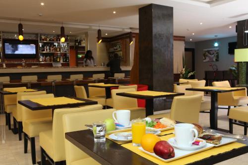 达喀尔Hotel VDN by Good Rade的一间餐厅配有桌椅,提供食物