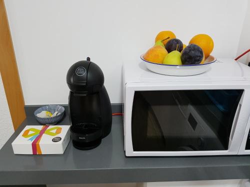 阿尔姆尼卡Apartamento centrico的咖啡壶和微波炉上的一碗水果