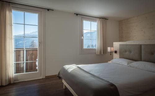 科尔蒂纳丹佩佐阿根廷别墅酒店的一间卧室配有床,还有两个窗户享有山景
