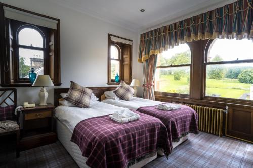 阿伯福伊尔Gartmore House Bed & Breakfast的一间卧室设有两张床和两个窗户。