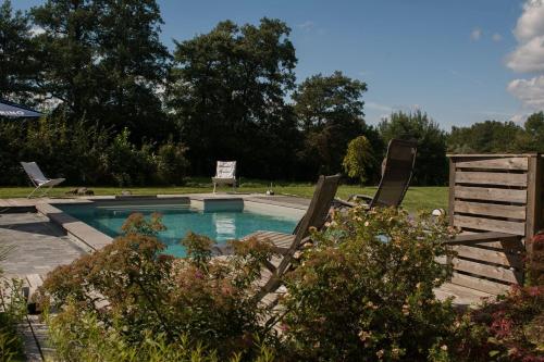 萨尔特-雷斯温泉Le Duplex de la Raveline的游泳池旁设有两把草坪椅