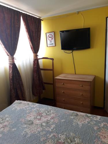 卡拉马Hotel Aymara的一间卧室配有一张床、一台电视和一个梳妆台