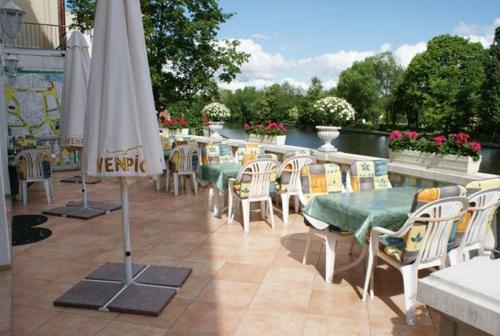 柏林库勃拉特河畔施普雷酒店的庭院配有桌椅和遮阳伞。