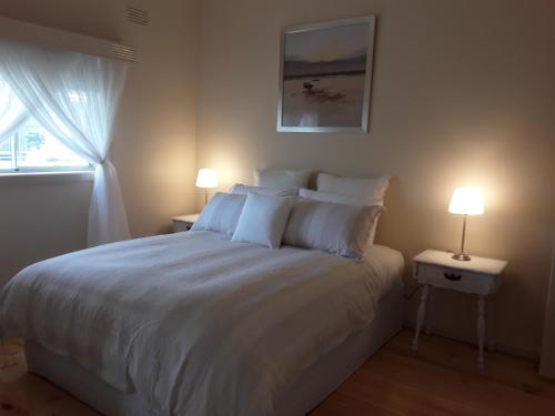 圣伦纳兹Bay Bell Cottage的一间卧室配有一张带两盏灯的大型白色床。