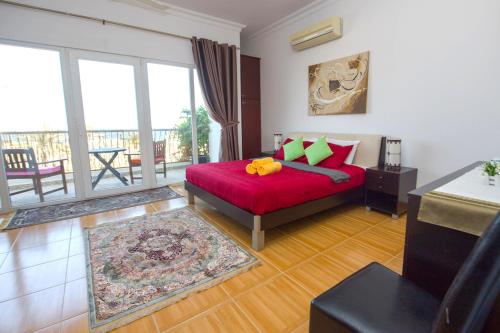 马斯喀特Lana Villa的一间带红色床的卧室和一个阳台