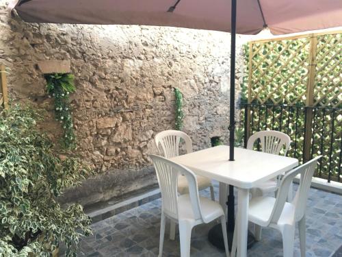 锡拉库扎卡萨奥提吉雅度假屋的庭院里配有白色的桌椅和遮阳伞