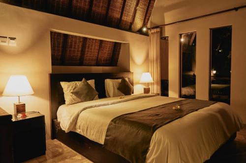 沙努尔花园别墅酒店的一间卧室配有一张大床和两盏灯。