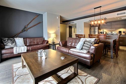 博普雷INITIAL - OLYMPIQUE - Mont-Sainte-Anne的客厅配有真皮沙发和桌子