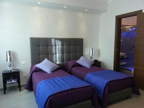 罗马多莫斯芬提斯酒店的一间卧室配有两张带紫色床罩和镜子的床