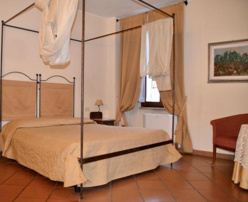 福利尼奥意大利酒店的一间卧室设有天蓬床和窗户。