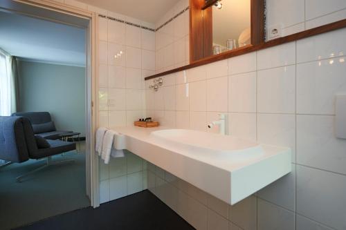 慕尼黑Parkhotel Obermenzing的一间带大型白色水槽和椅子的浴室