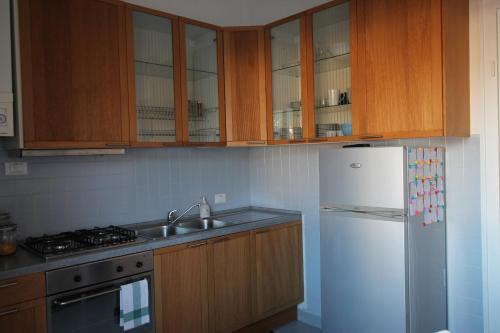 斯培西亚Interno24 Apartment的厨房配有木制橱柜和白色冰箱。