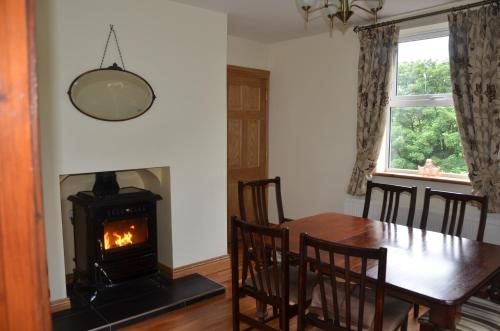 CarrigallenBridgefield House的一间带桌子和燃木炉的用餐室