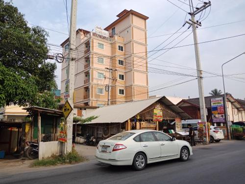 华欣班帕克山姆阿农公寓式酒店的停在高楼前的白色汽车