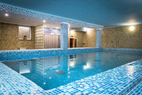 罗夫诺阿文格酒店的浴室里设有一个蓝色瓷砖的大型游泳池