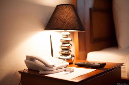 利伯维尔Hotel Adagio的电话和桌子上的一盏灯,床上
