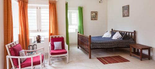 GonikoppalCoorg Kolamotte的一间卧室配有一张婴儿床、两把椅子和一张桌子