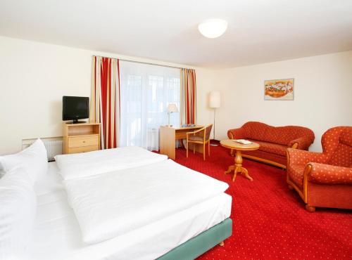 慕尼黑英格里申伽藤贝德斯汀酒店的酒店客房配有白色的床和沙发。