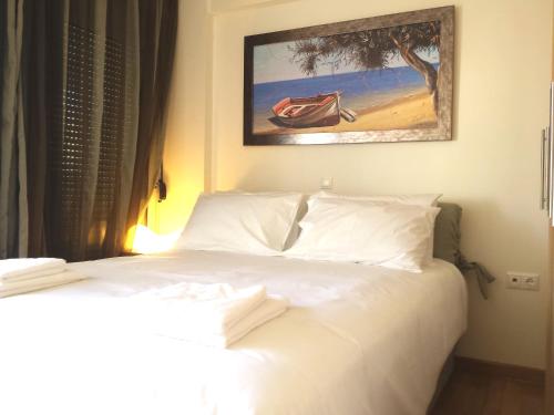 雅典Elvita Athens Sea View Maisonette的卧室配有一张白色床,墙上挂有绘画作品