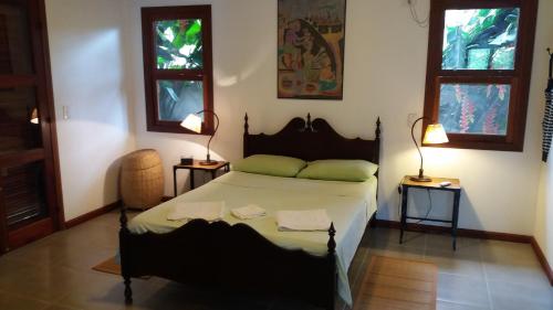帕拉蒂Bangalôs Parque Verde的一间卧室配有一张带两张桌子和两个窗户的床。