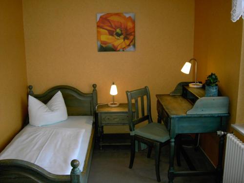 BergaLandhotel am Fuchsbach的一间卧室配有一张床、一张桌子和一把椅子