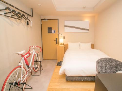 岛田HATAGO INN Shizuoka Yoshida IC的一间卧室配有一张床和一辆红色自行车
