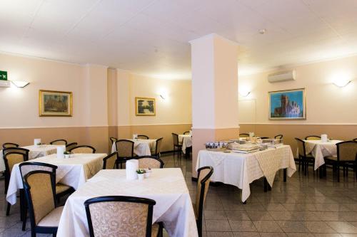 米兰皮克洛酒店的餐厅配有桌椅和白色桌布