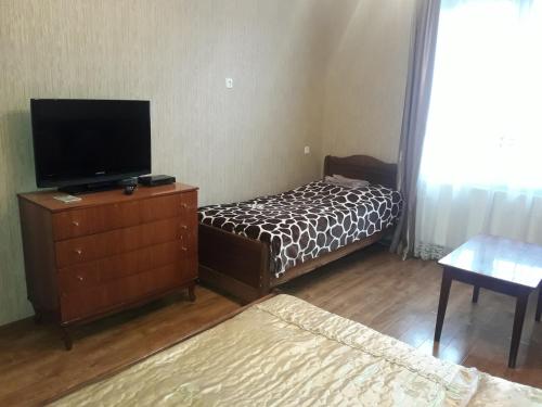 博尔若米zeiko s guesthouse的一间卧室配有一张床和一个带电视的梳妆台