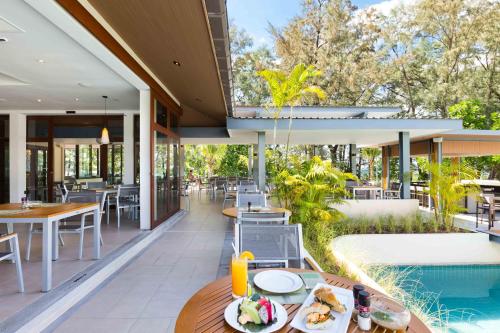 奈扬海滩Dewa Phuket Resort & Villas的一个带桌椅的户外庭院和一个游泳池