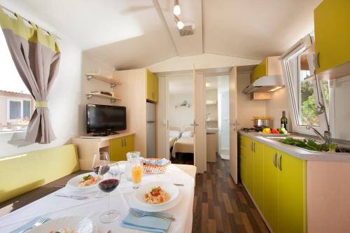 诺维格勒伊斯特拉Sirena Mobile Homes的厨房配有黄色橱柜和餐桌