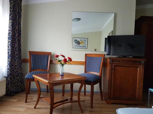 柏林欧亚瑟膳食公寓酒店的一间配备有桌子和两把椅子及一台电视的房间