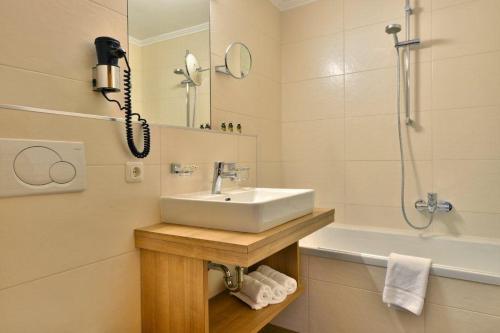 延巴赫Gasthof und Hotel Rieder GmbH的一间带水槽和淋浴的浴室以及一部电话