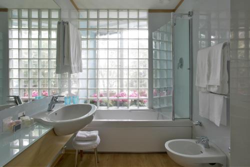 米兰斯帕达里大教堂酒店的一间带两个盥洗盆、浴缸和窗户的浴室