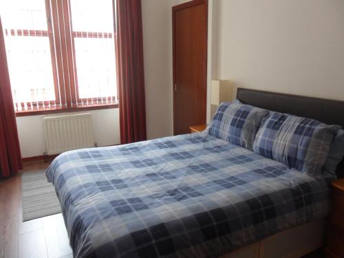 格拉斯哥The Exeter的一间卧室配有一张带蓝色铺面毯子的床