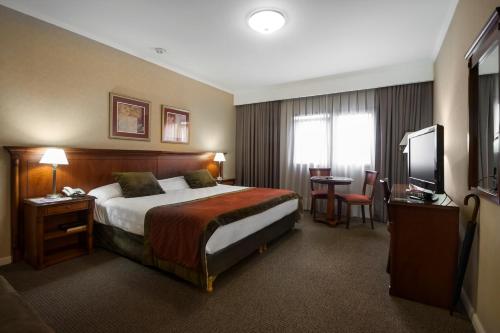 圣米格尔·德·图库玛图库曼中心商务套房酒店的酒店客房,配有床和电视