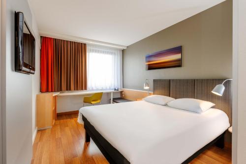 不莱梅布莱梅中心宜必思酒店的酒店客房设有一张白色大床和一个窗户。