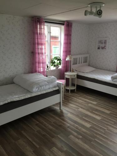尤城Rolösa的一间卧室设有两张床,窗户配有粉红色的窗帘