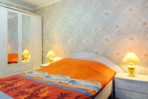 沃尔库塔Apartment TwoPillows on Lenina 52的一间卧室配有一张带橙色床单和鲜花的墙壁床。
