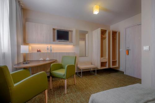 华沙雷坦酒店的一间设有两把椅子、一张桌子和一台电视的房间