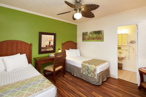 檀香山太平洋码头酒店的一间卧室配有两张床、一张桌子和一个水槽