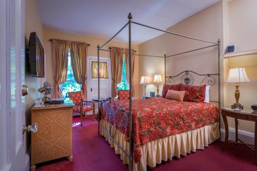 库珀斯敦The Inn at Cooperstown的一间卧室配有一张带红色床罩的天蓬床