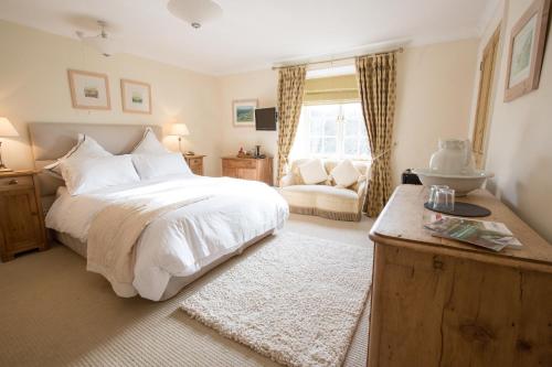 Aveton GiffordCourt Barton Farm的卧室配有一张白色大床和一把椅子