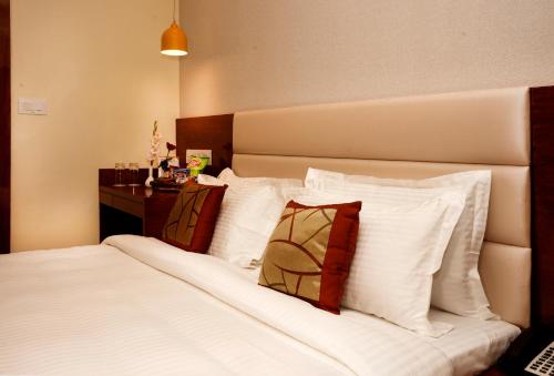 巴特那Amalfi Grand的配有白色枕头的床的酒店客房