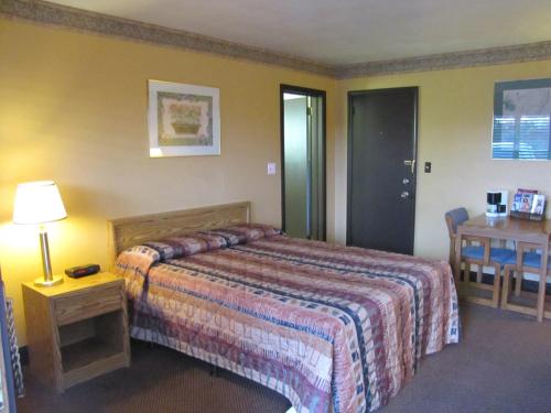 Mercer默瑟-格罗夫市科洛尼酒店的酒店客房配有一张床、一张桌子和一张桌子。