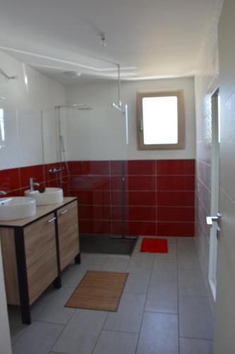 内维兹Maison bord de mer avec jacuzzi的浴室设有两个水槽和红色的墙壁